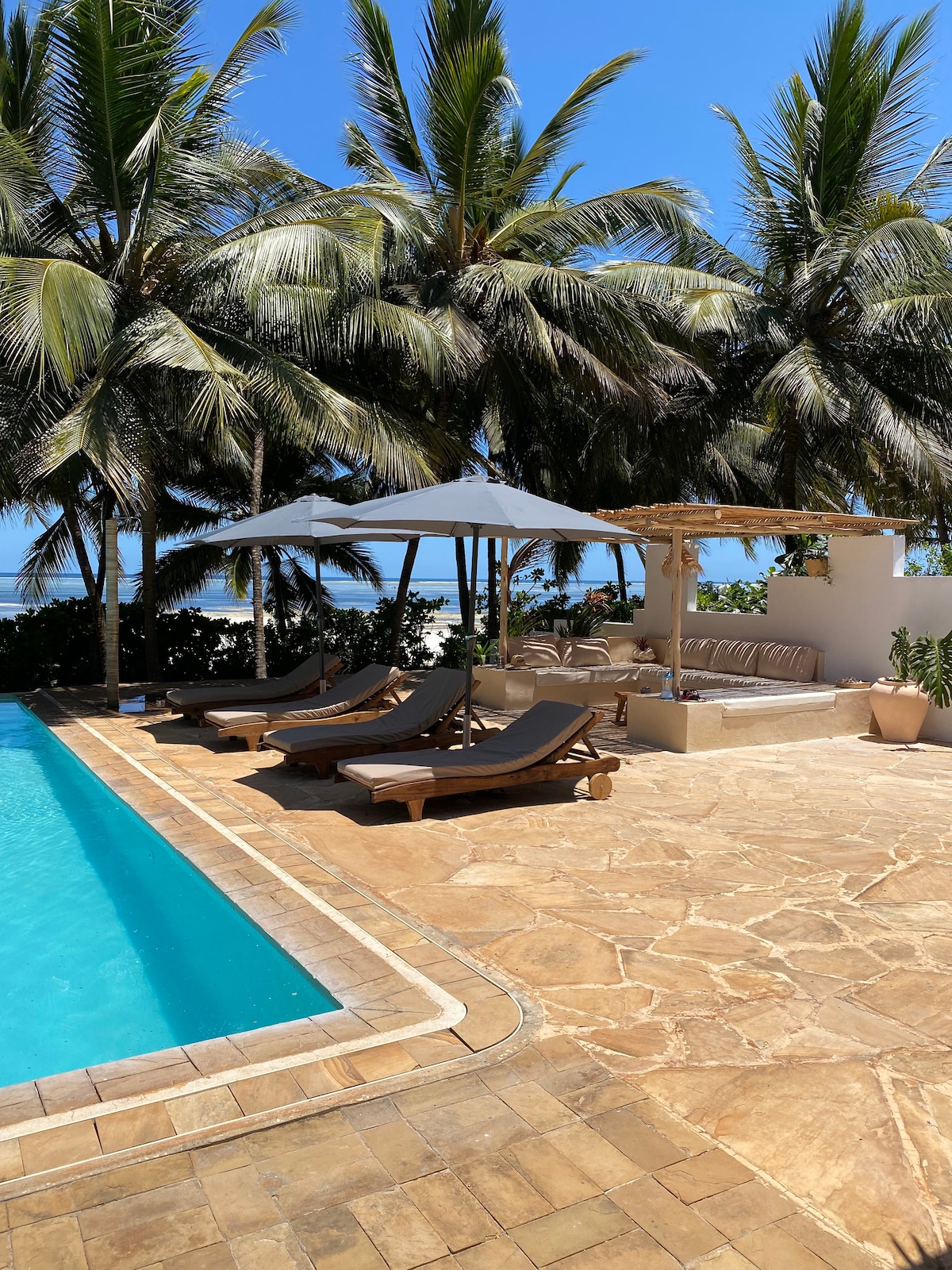 Stone terrace, pool, pergola and ocean beyond